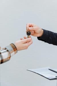 Duas pessoas segurando uma chave de carro, simbolizando a entrega ou compra de um veículo