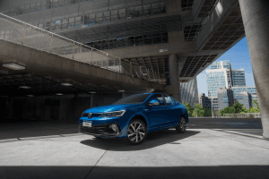 Volkswagen Virtus azul estacionado em ambiente de cimento, com fundo minimalista e tons acinzentados destacando o design do sedã.