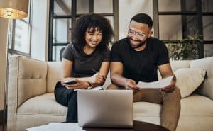 Casal sentado à mesa organizando finanças, analisando papéis e calculadora, em momento de planejamento financeiro