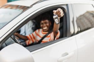 beaming-woman-proudly-presents-car-keys-in-vehicle