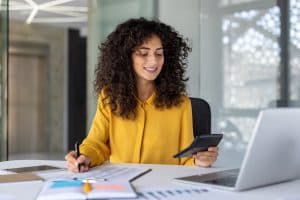 Mulher olha calculadora, organiza finanças para financiamento