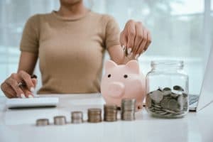 mulher coloca dinheiro no seu porquinho, organização financeira.