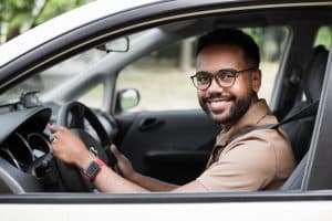 homem sorrindo ao volante, feliz após conquistar seu carro seminovo com financiamento aprovado.