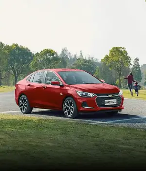 Carro Onix na cor Vermelha estacionado em um parque
